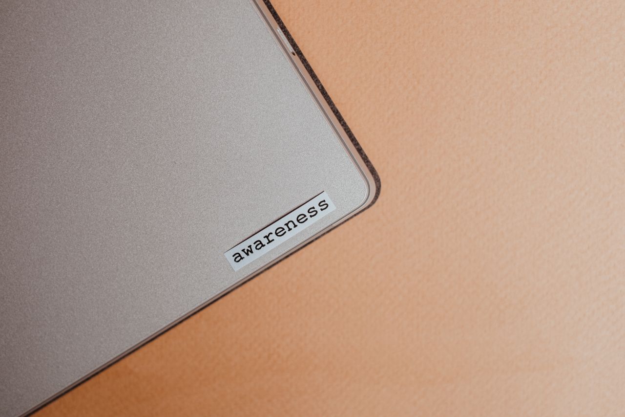 Close-up of a beige laptop featuring an awareness sticker, suggesting mindfulness and digital organization.